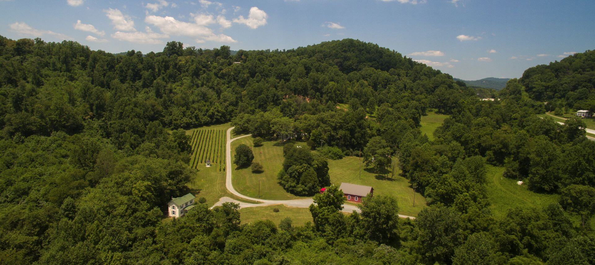 Overhead arial view of white manor house and yellow farmhouse on expansive grounds.