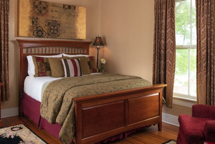 Elegant wooden sleigh bed covered insumptuous bedding in large airy room.