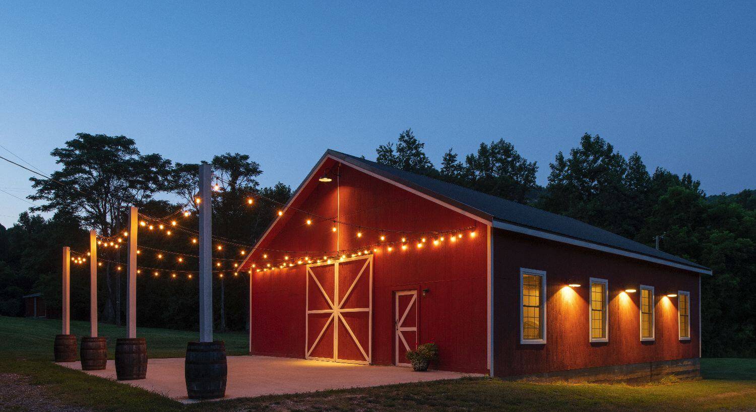 Red barn venue lit with edison lights at dusk