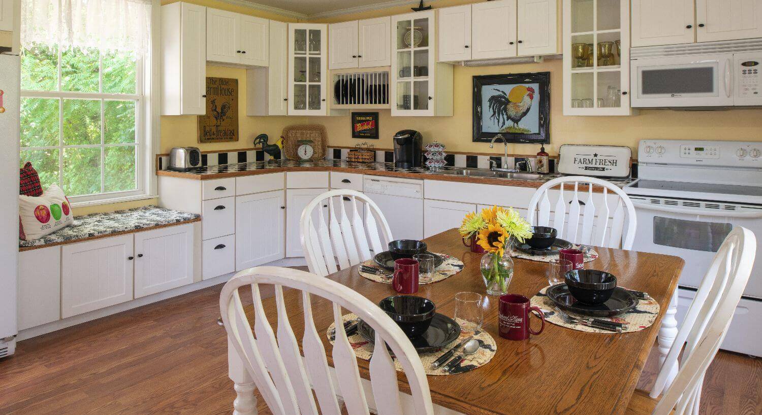 Cheery white and yellow farmhouse kitchen with table set for dining. 