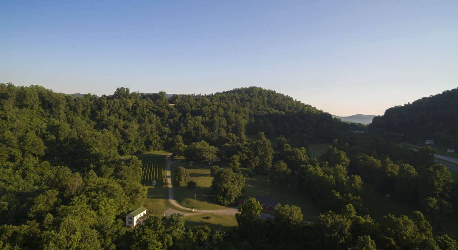 Overhead arial view of white manor house and yellow farmhouse on expansive grounds.